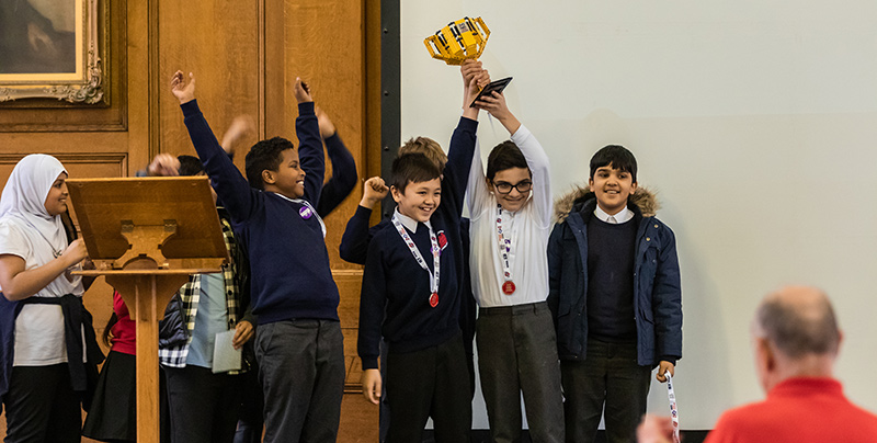Victorious team holds aloft their trophy at FIRST LEGO League event