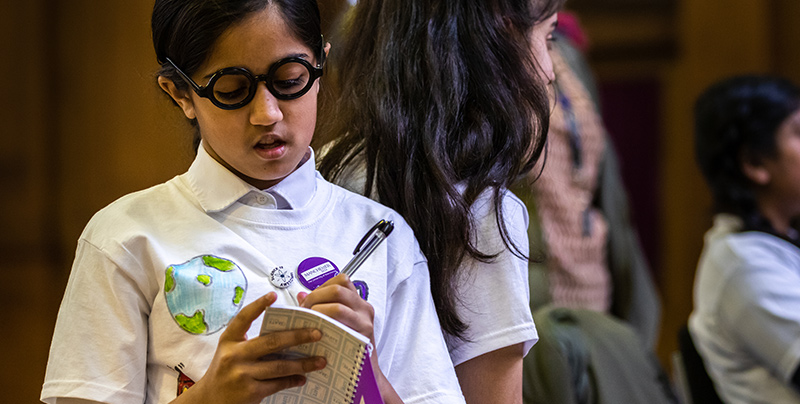Girl taking notes at FIRST LEGO League event