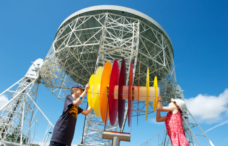 Children play in front of telescope