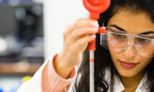 Scientist wearing protective glasses and holding a pipette