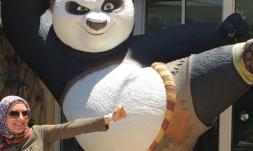 Dr Zahra Montazeri doing a kung fu kick in front of a large Kung Fu Panda statue.