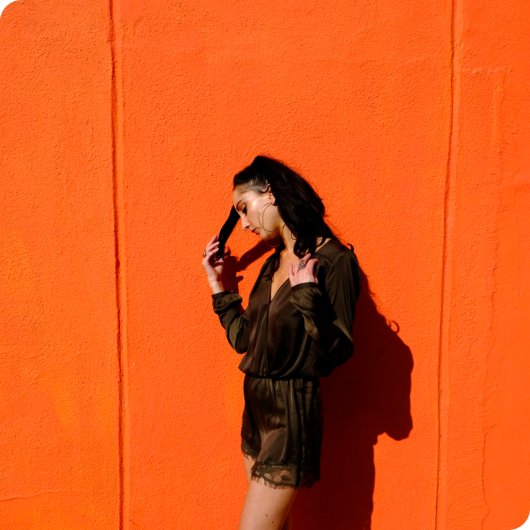 Female model posing in front of orange wall