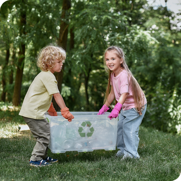 A boy and smiling girl outside holding a recycling box together