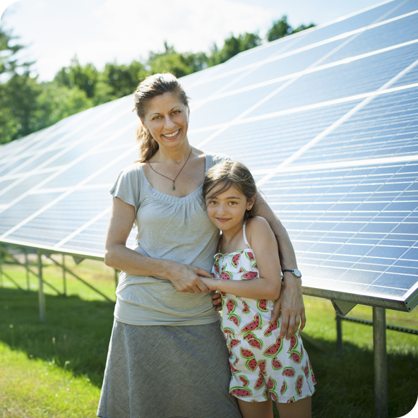 A child and her mother in the fresh open air, beside solar panels on a sunny day